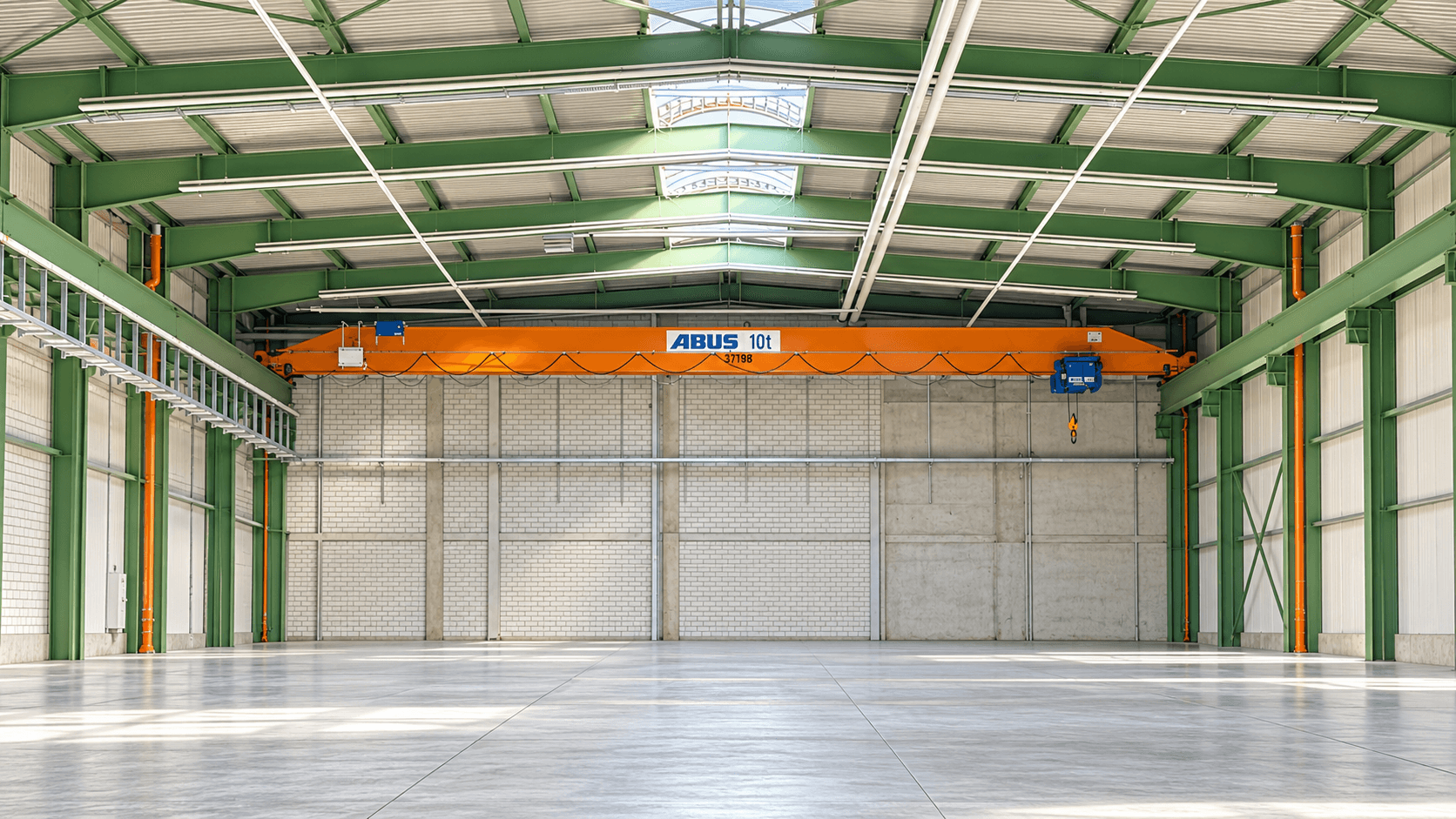 Leere Industriehalle mit grünen Stahlträgern, einem orangefarbenen ABUS-Laufkran und glänzendem Betonboden unter Oberlichtern.